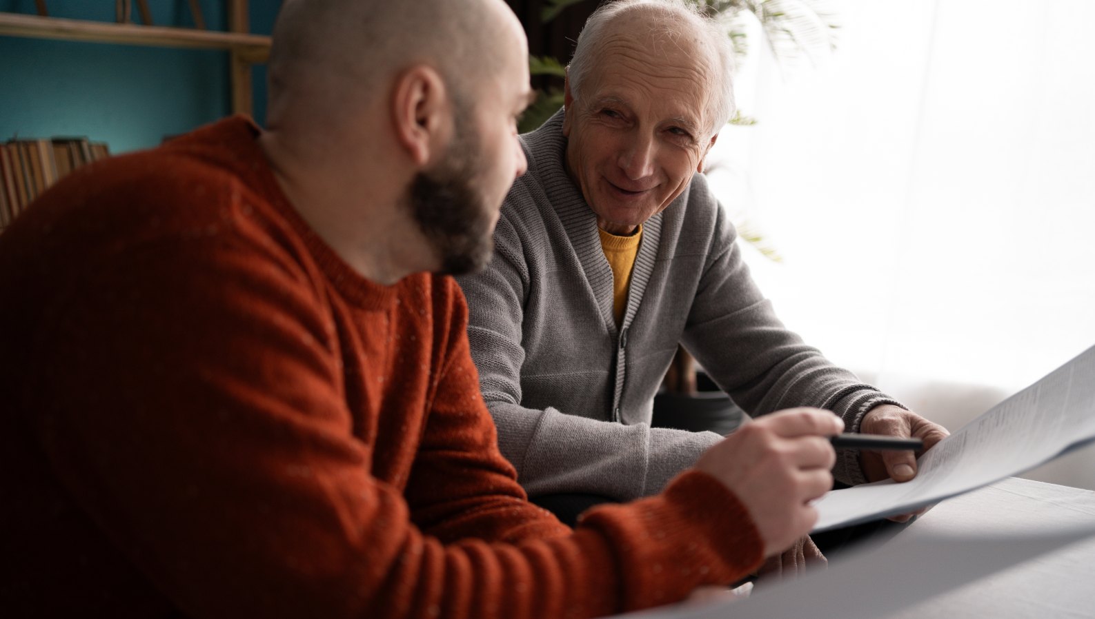 An adult son helping his elderly father with paperwork and finances