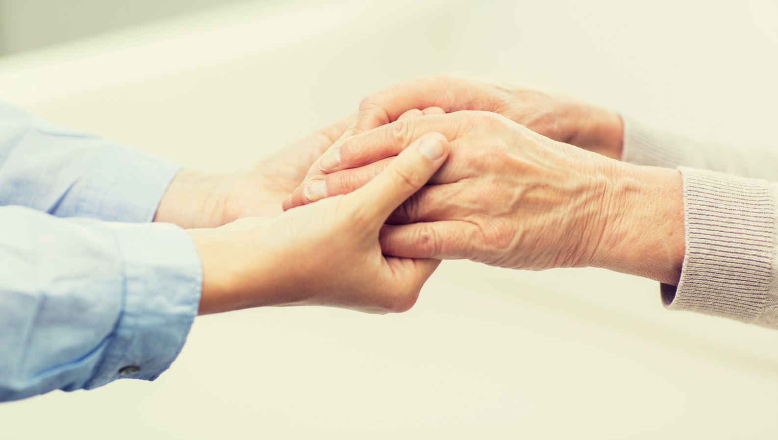 A caregiver gently holding a seniors hand in reassurance