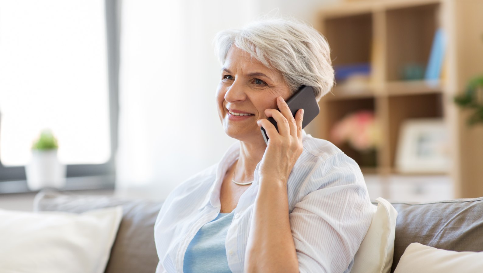 A cheerful senior woman staying connected on the phone at home