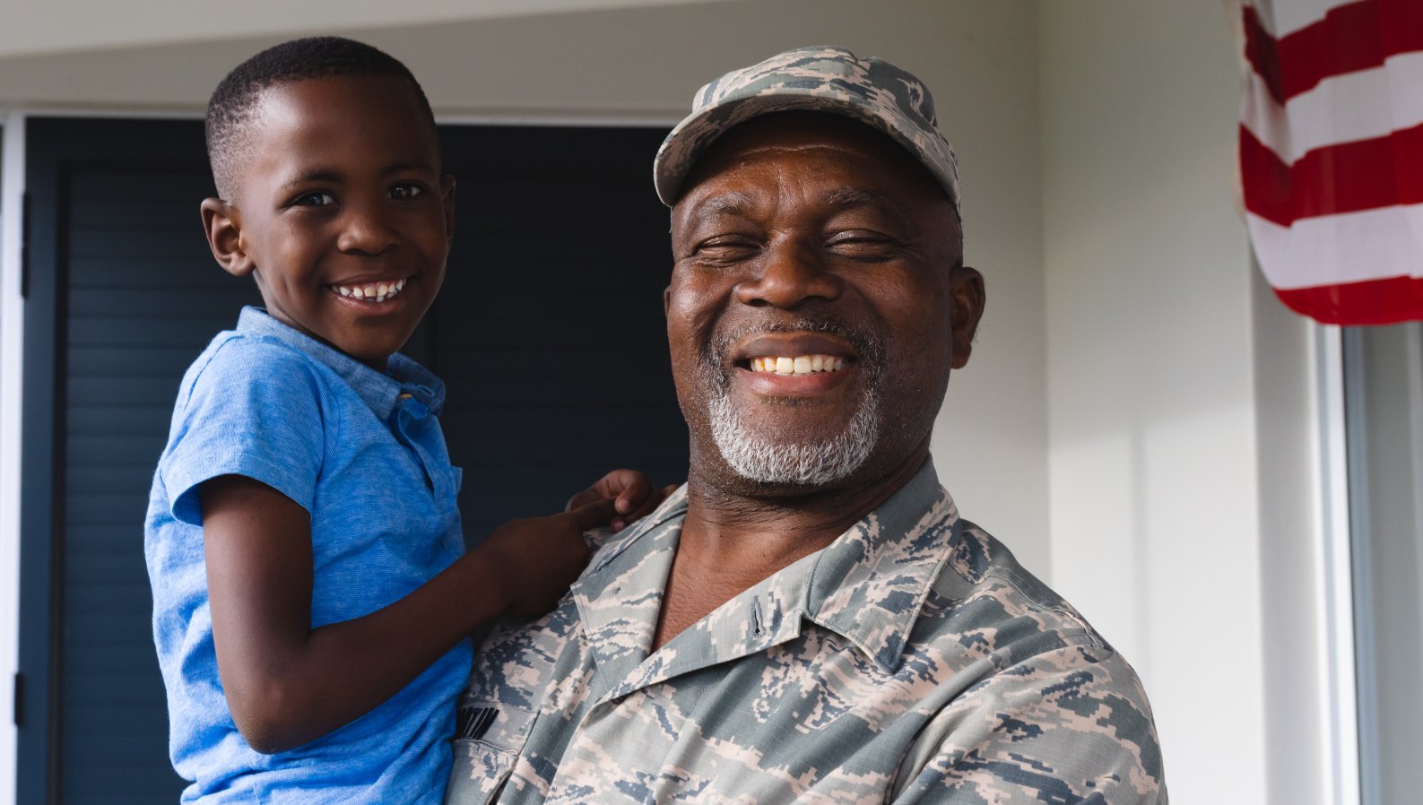 A smiling senior military veteran at home with his grandson